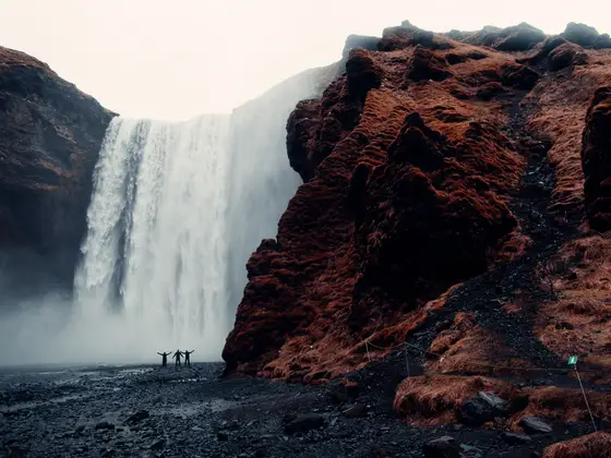 Travellers standing before Skogafoss waterfall